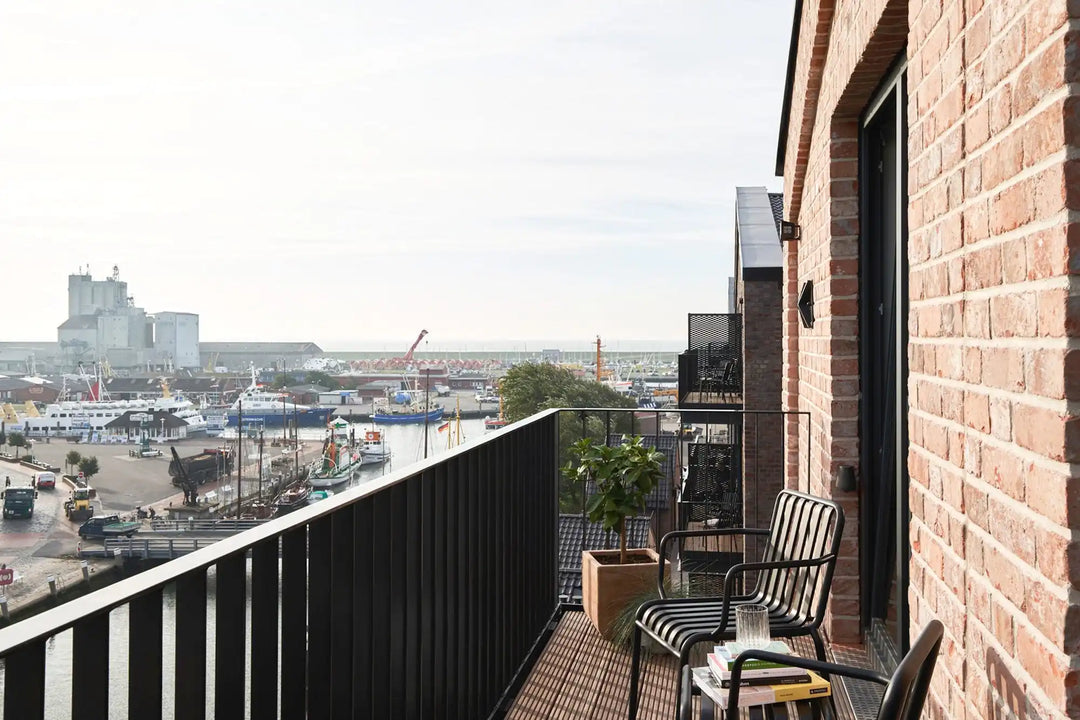 Balkon mit Schaukelstühlen mit Blick auf einen Hafen.