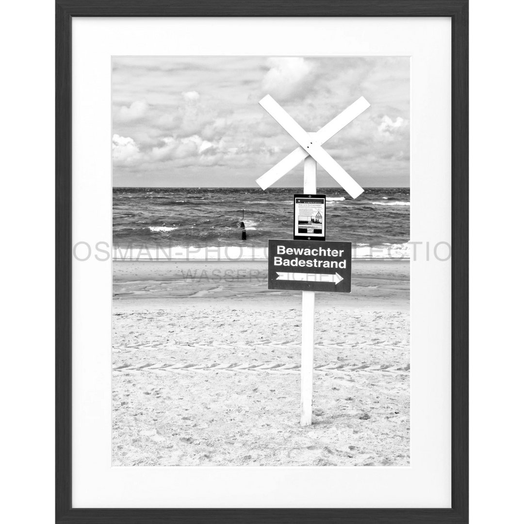 Warnschild mit weißen Querbalken und Text Bewachter Badestrand am Strand von Sylt