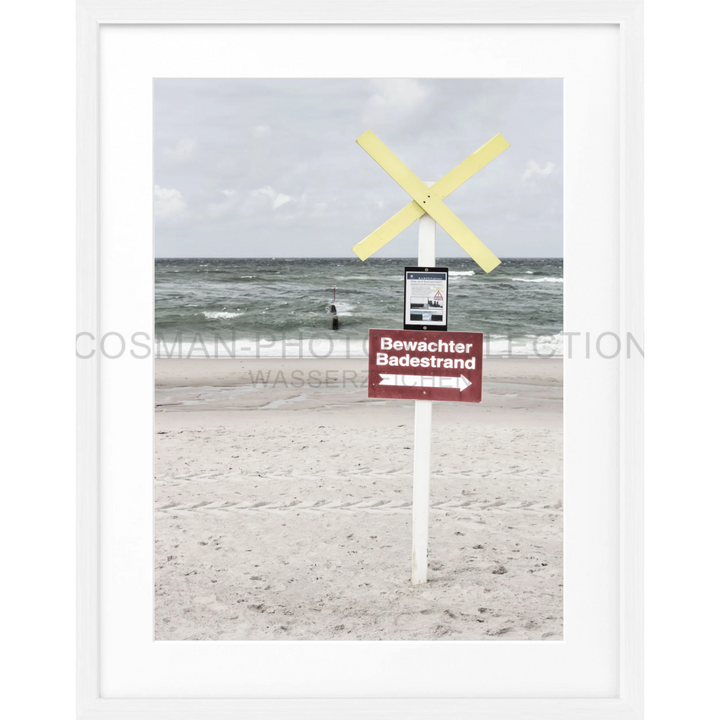 Warnschild mit gelben Kreuzmarkierungen an einem weißen Pfosten am Strand von Sylt