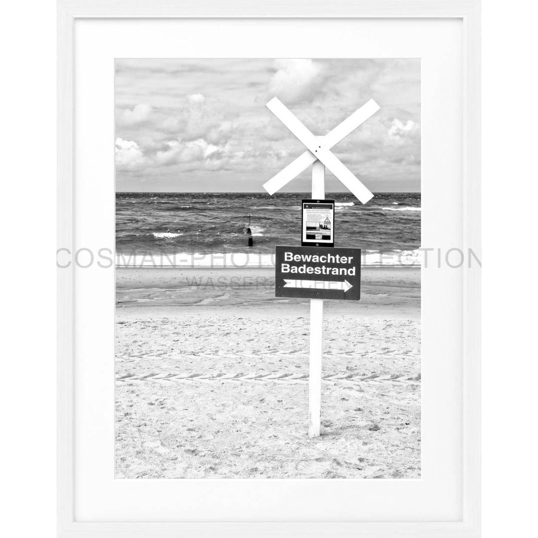 Weißes Holzschild mit der Aufschrift Bewachter Badestrand und X-Zeichen oben