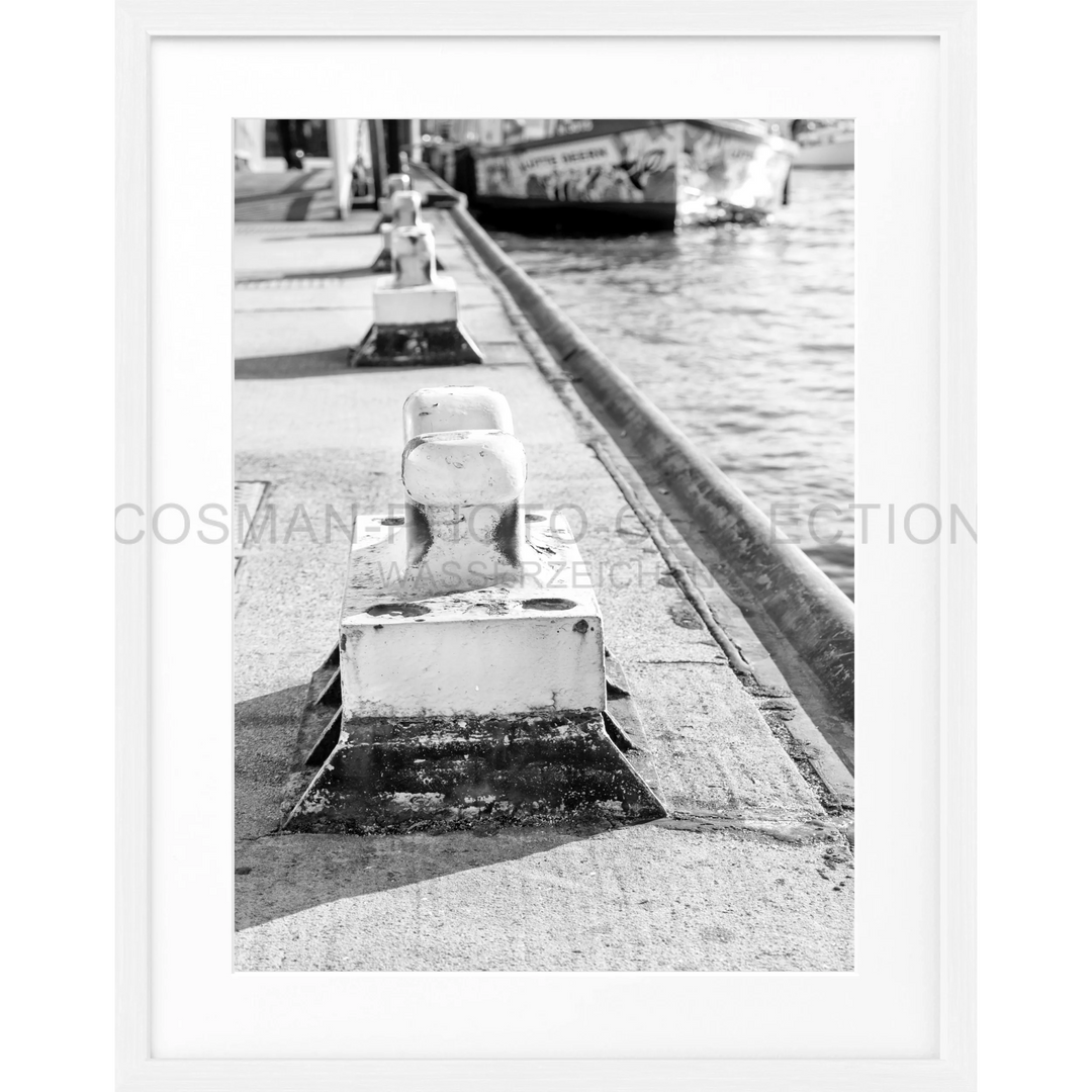 Betonpoller mit diagonal gestreiften Markierungen am Wasserufer in Hamburg Hafen