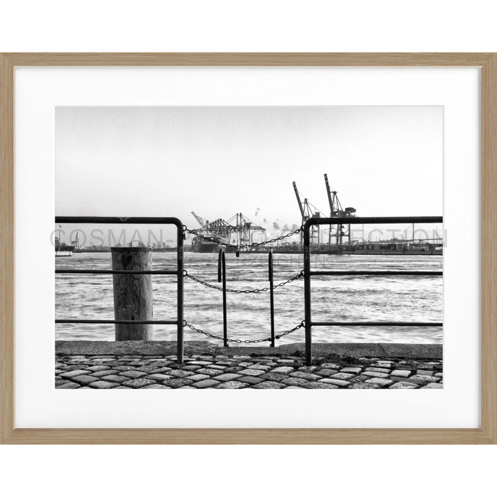 Metallzaun mit Blick auf den Hamburger Hafen und Containergabeln