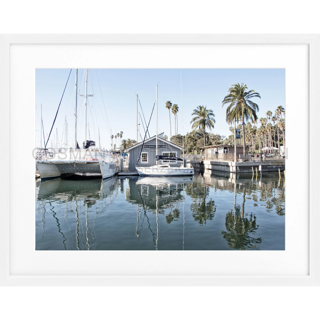 Sailboats und ein Bootshaus spiegeln sich im ruhigen Hafenwasser von Santa Barbara