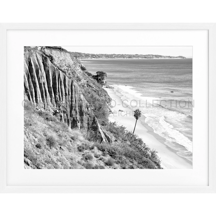 Küstenklippe mit Erosionsstriationen über einem Strand und Palmen in Malibu