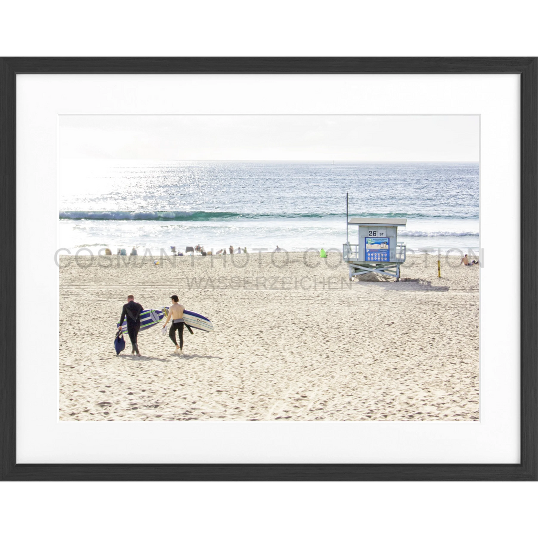 Zwei Surfer tragen ihre Surfboards über den Sandstrand in Manhattan Beach