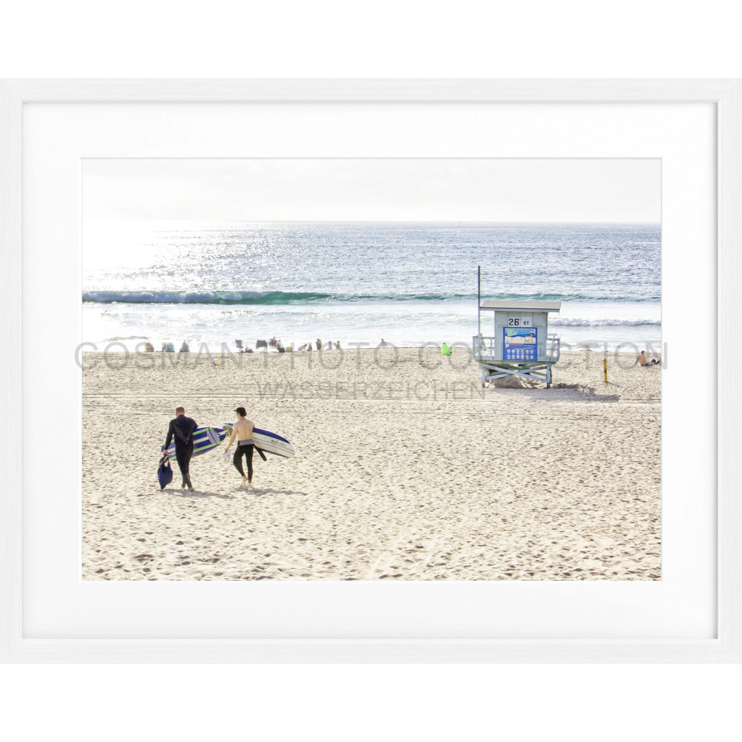 Zwei Surfer tragen ihre Surfbretter über den Sandstrand von Manhattan Beach