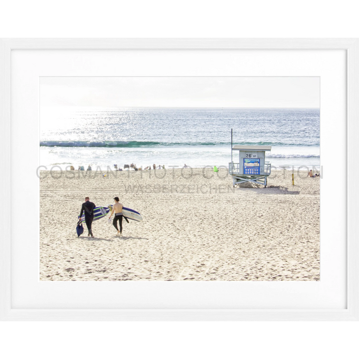 Zwei Surfer tragen ihre Surfbretter über den Sandstrand von Manhattan Beach