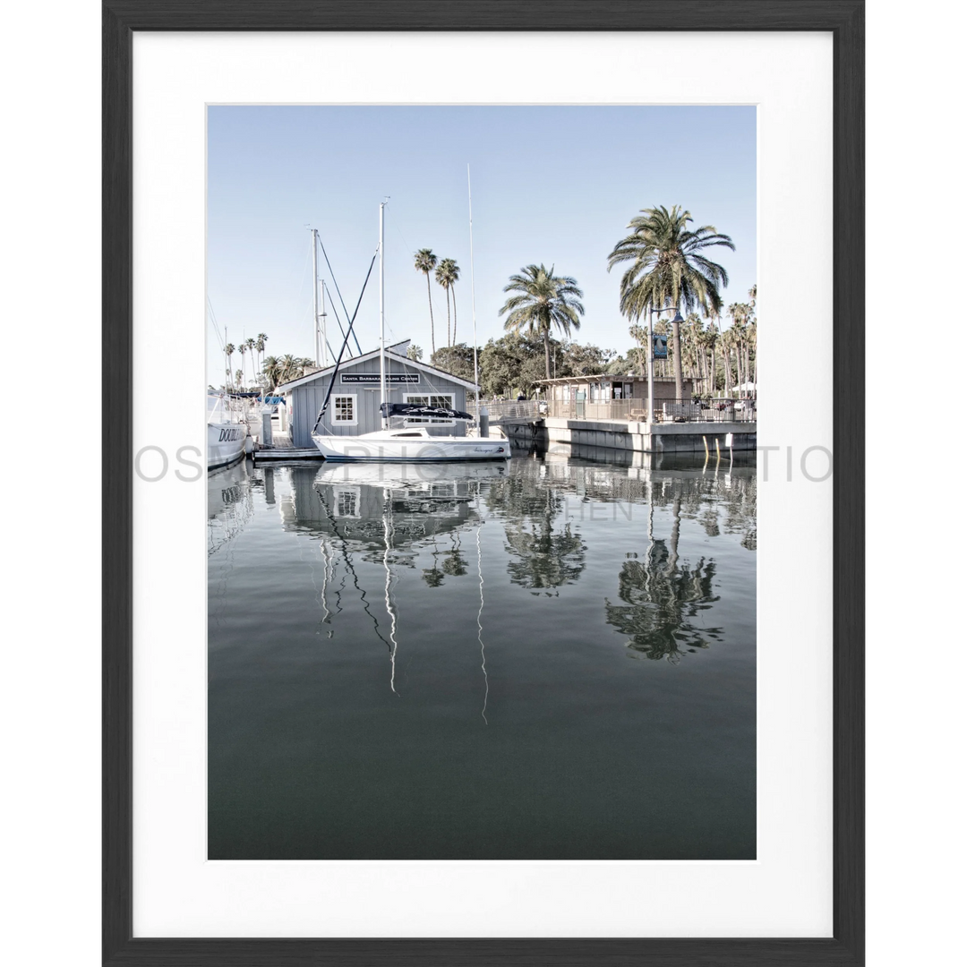 Weißes Boot am Dock mit Palmenreflexionen im ruhigen Wasser in Santa Barbara