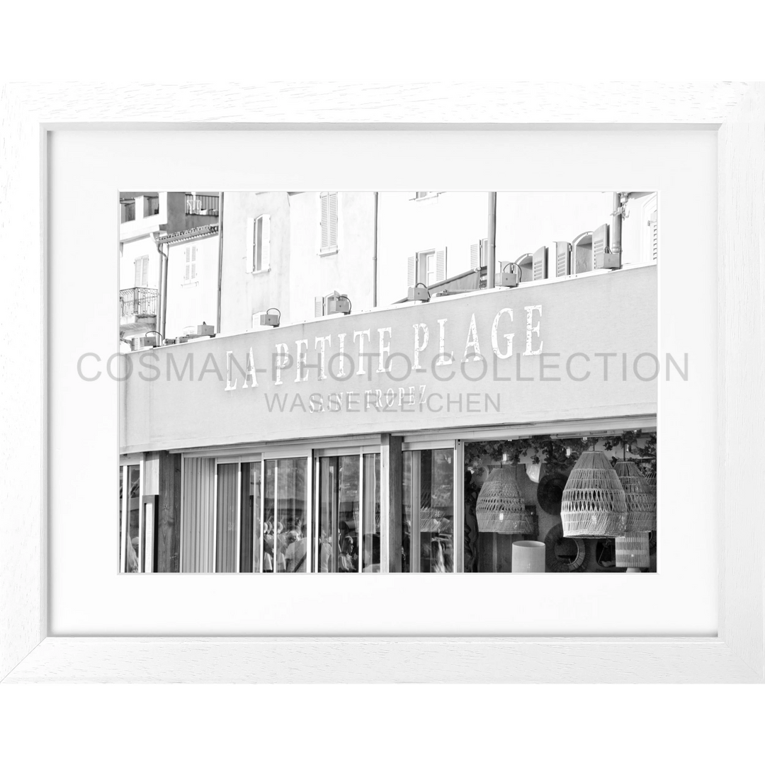 Schwarzweißfotografie eines Geschäfts mit PETITE PLAGE-Schild und hängenden Körben