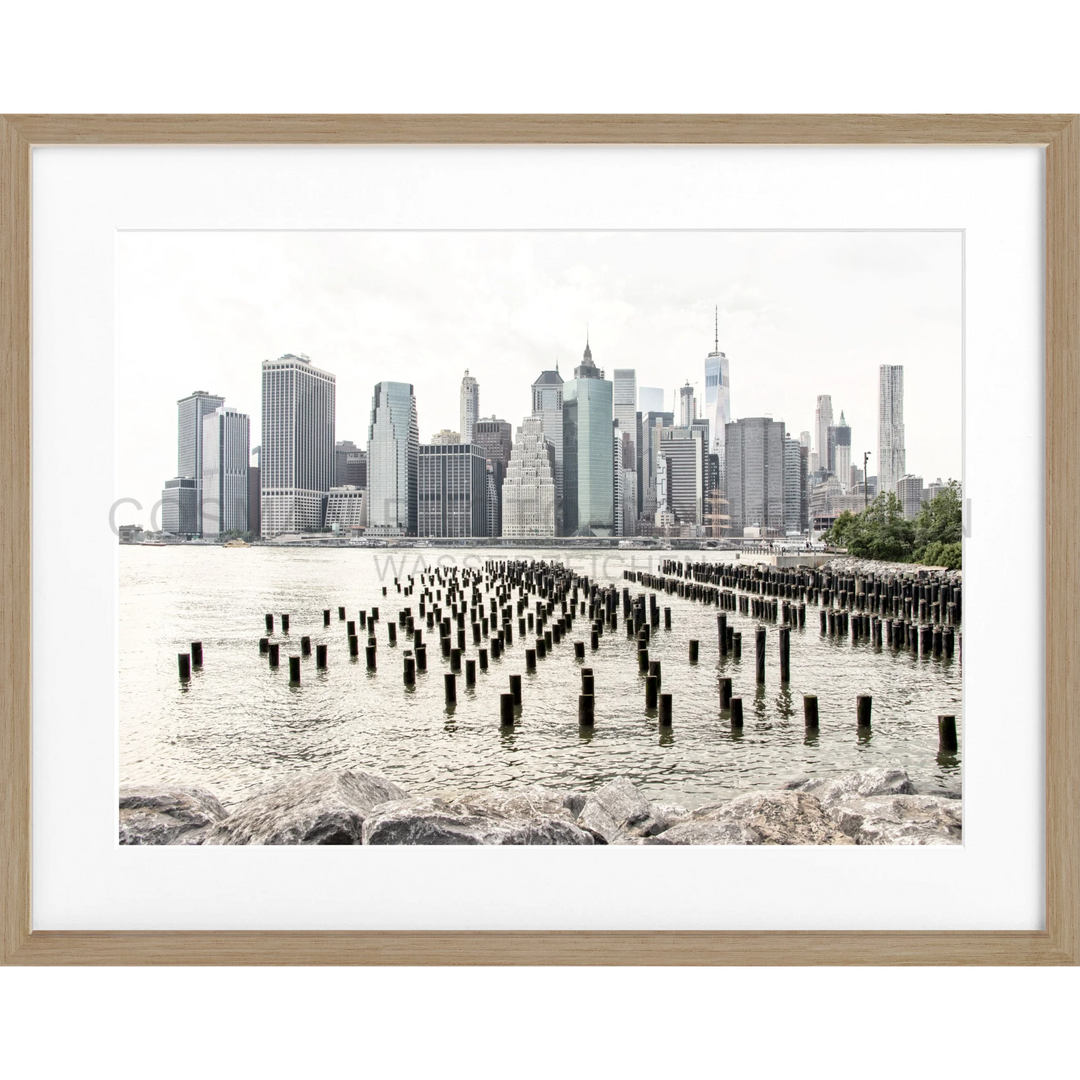 Gerahmtes Schwarz-Weiß-Foto der Manhattan Skyline mit alten Pfählen im Vordergrund