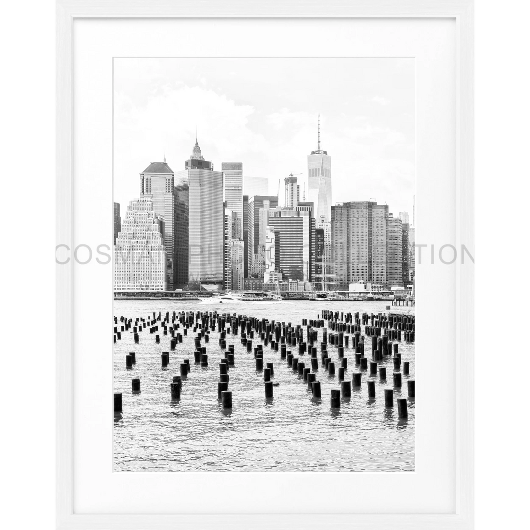 Schwarz-weiß-Fotografie der Manhattan Skyline mit Holzpfählen im Vordergrund