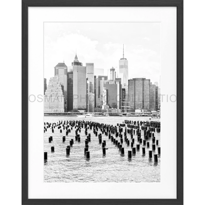 Schwarz-weiß-Fotografie der Skyline von Manhattan mit alten Pierpfählen im Vordergrund