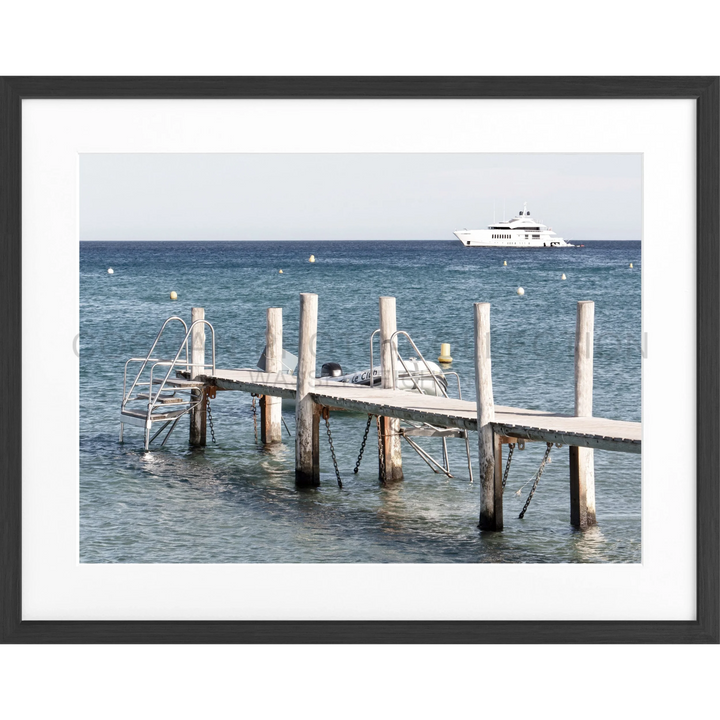 Holzpier mit weißen Pfosten, der ins blaue Wasser führt, für Poster Steg Le Club 55