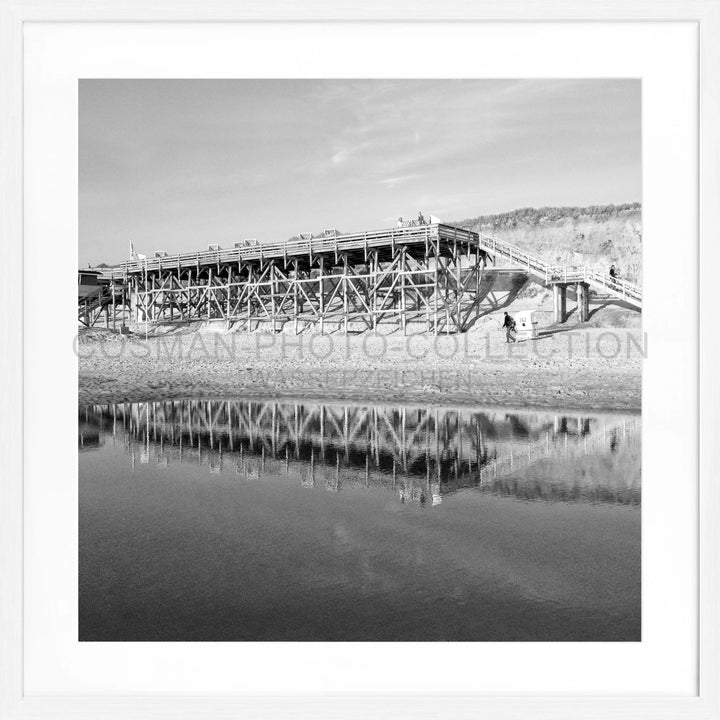 Holzstützenbrücke spiegelt sich im ruhigen Wasser, Poster Sylt Strand Kampen SY55Q