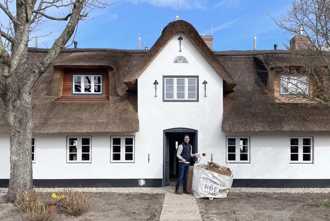 Traditionelles reetgedecktes Haus mit weißen Wänden und schwarzem Zierrat.